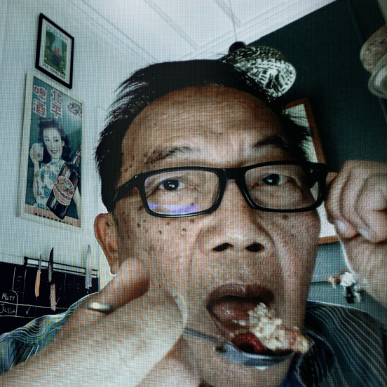 Photo of Asian man with black glasses spooning food into his mouth