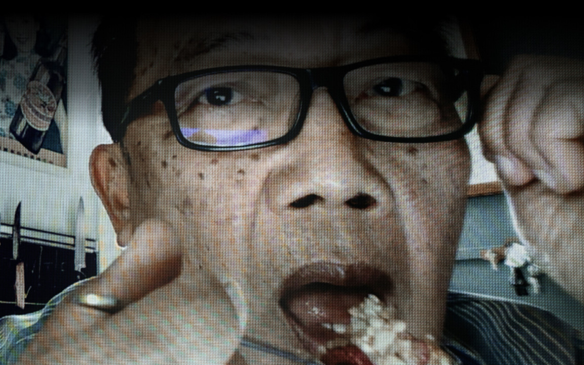 Photo of Asian man with black glasses spooning food into his mouth