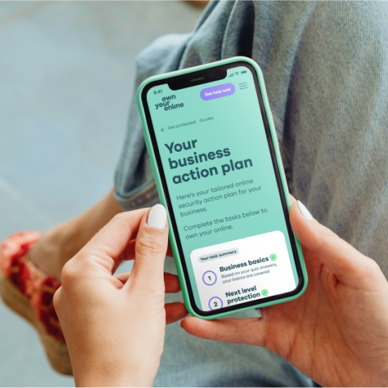 Photo of a woman's hands holding a mobile phone with webpage showing the words Your business action plan.