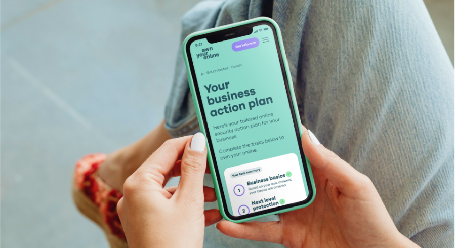 Photo of a woman's hands holding a mobile phone with webpage showing the words Your business action plan.