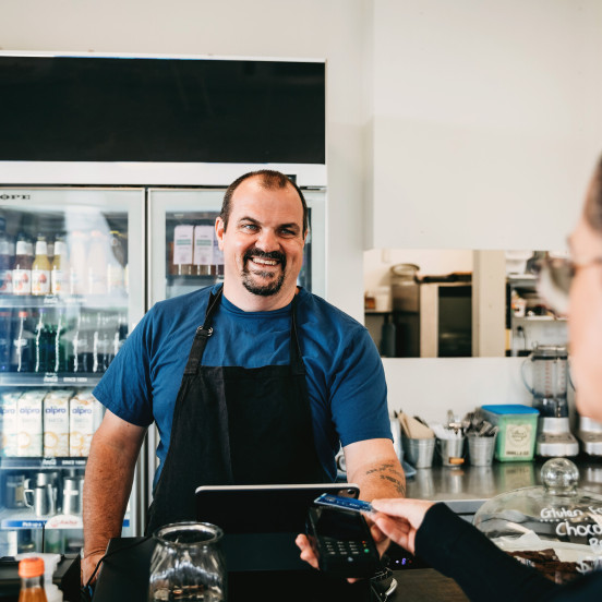 Cafe owner serving customer at the till