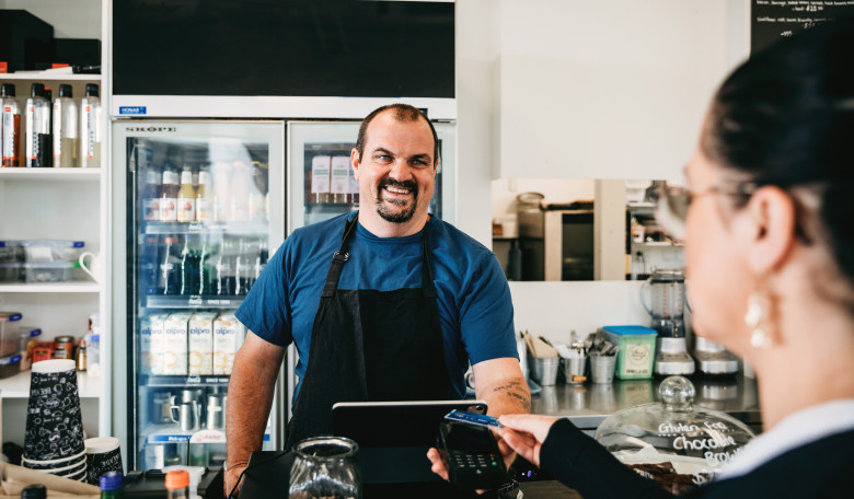 Cafe owner serving customer at the till