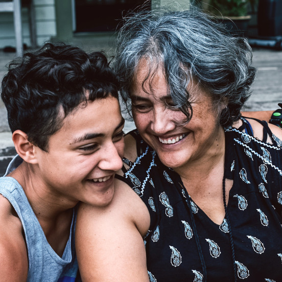 Grandmother and child laughing together with the child's arm around her shoulder