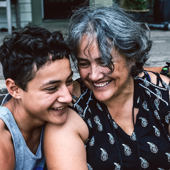 Grandmother and child laughing together with the child's arm around her shoulder