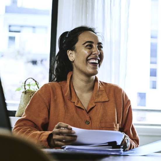 Woman sitting at desk holding documents and smiling