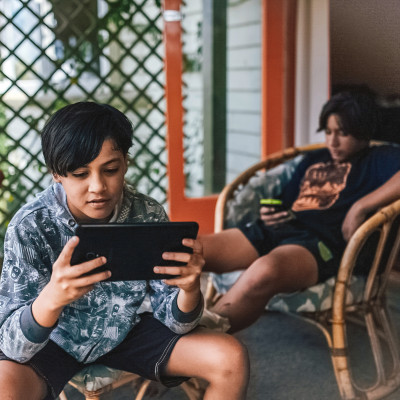 Three young boys sitting on wicker chairs all on their devices