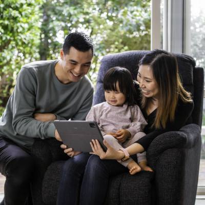 Mum, Dad and child sitting together and looking at a tablet