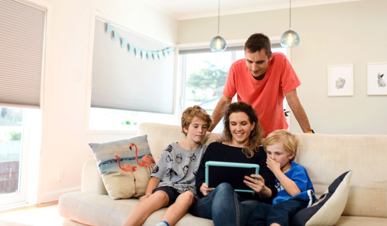 Family sitting on the couch all looking at a laptop screen